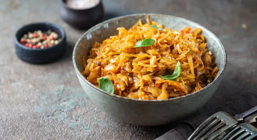 Cavolo stufato, un classico da provare per scoprire cosa mangiare a Varsavia. Servito in una ciotola con erbe fresche, pepe e sale.