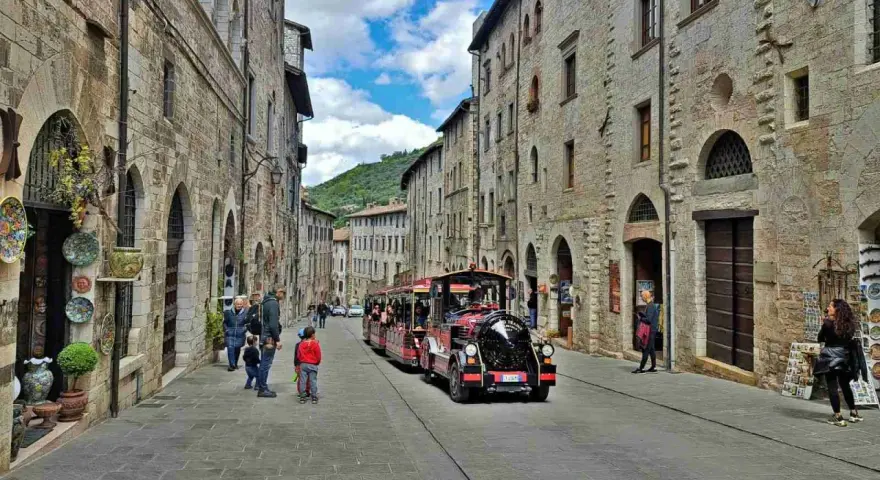 Treno turistico attraversa una strada acciottolata di Gubbio, un'idea per cosa vedere a Gubbio in un giorno.