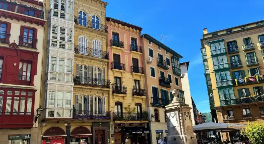 Edifici colorati con balconi in ferro battuto e una fontana in una piazza. Perfetto per scoprire cosa vedere a Bilbao in 3 giorni.