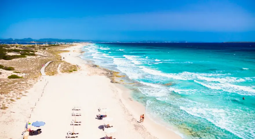 Spiaggia da sogno in Spagna dove andare al mare: sabbia bianca, acque turchesi e un sentiero tra le dune.