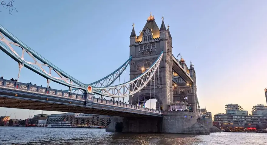 La Tower Bridge illuminata, un'icona per chi ama viaggiare a Londra, si specchia sul Tamigi al tramonto.