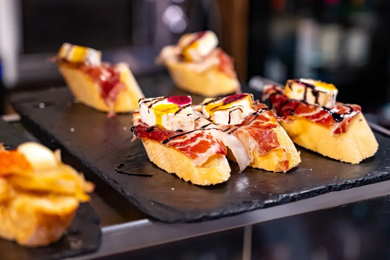 Deliziosi pinchos con prosciutto, formaggio e salse, perfetti per scoprire cosa mangiare a Barcellona.