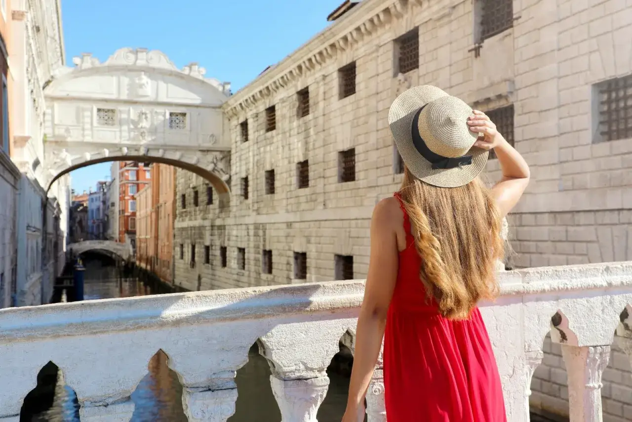 Donna con cappello osserva il Ponte dei Sospiri, un'icona da non perdere se ti chiedi cosa vedere a Venezia in 3 giorni.