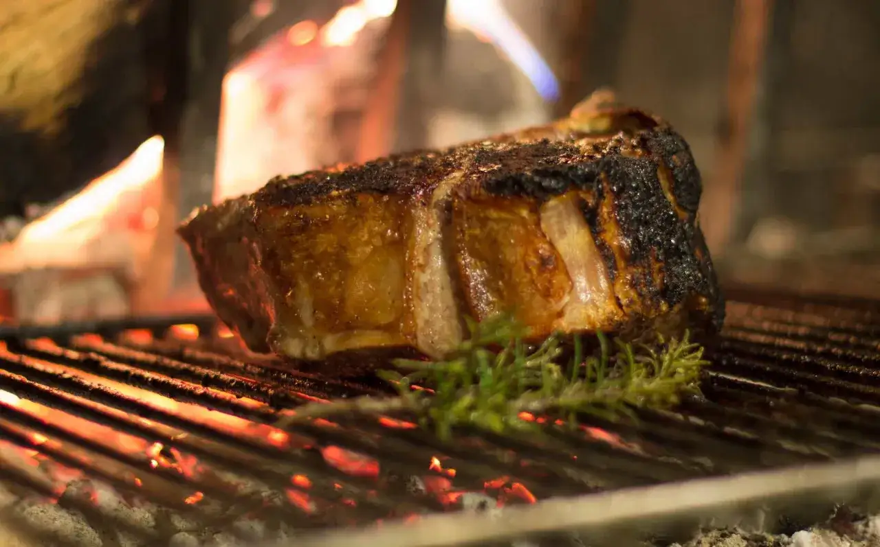 Bistecca fiorentina, un'icona di Firenze, cuoce lentamente sulla brace ardente, sprigionando profumi irresistibili.