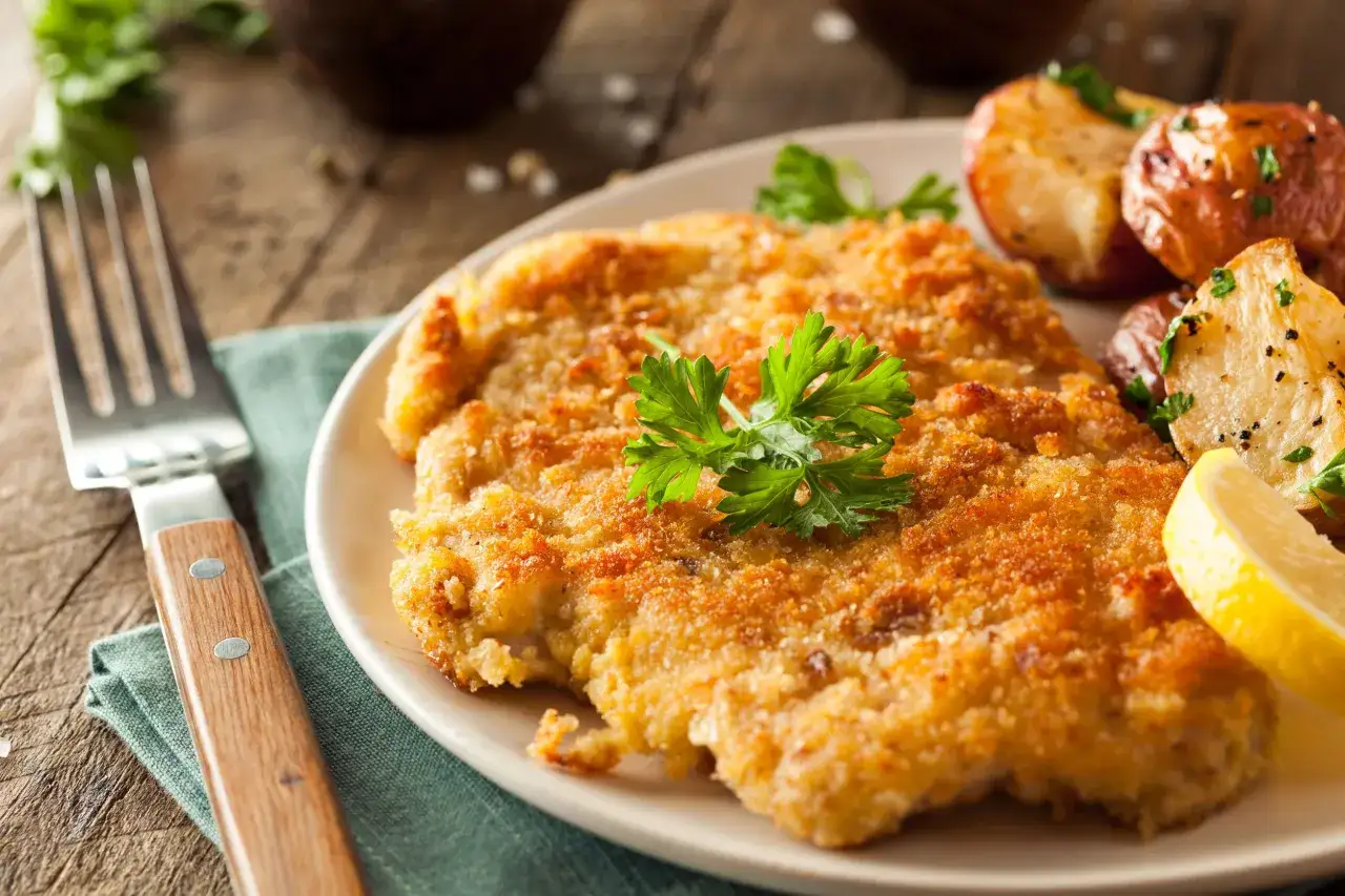 Wiener Schnitzel con patate arrosto e limone, un classico da provare per scoprire cosa mangiare a Vienna.