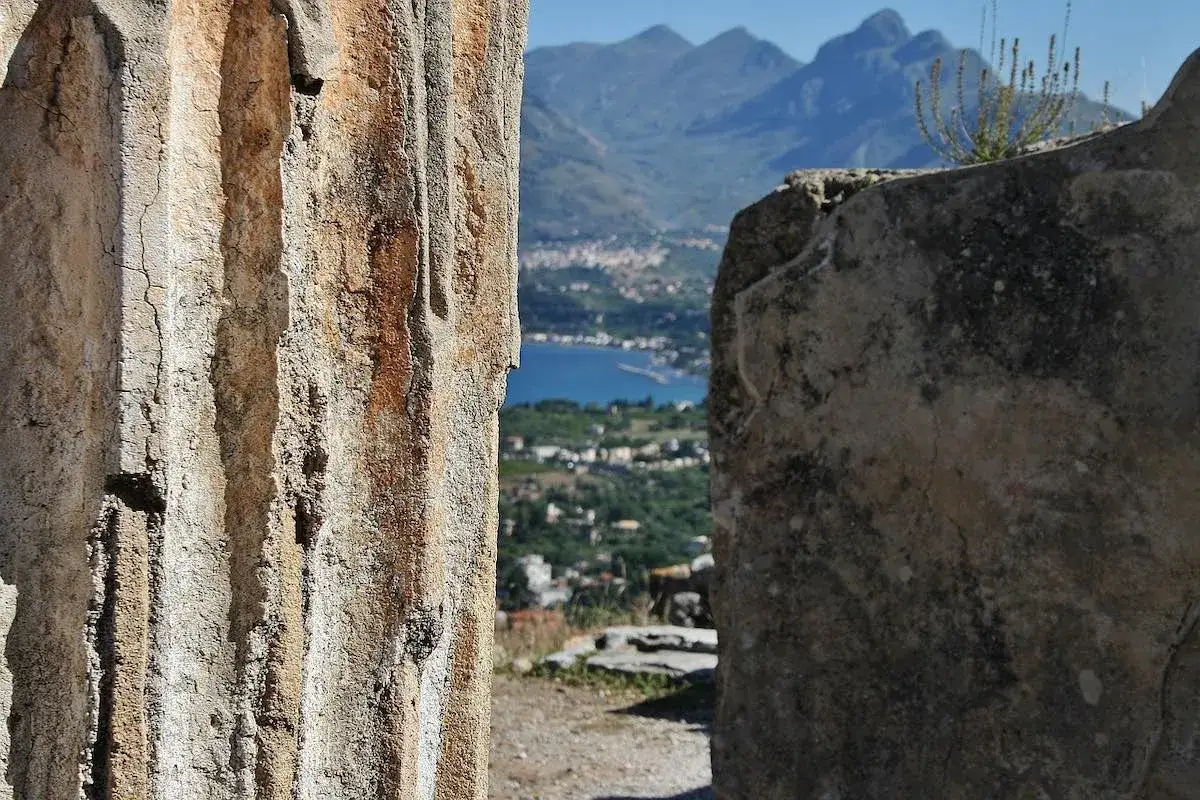 Tra antiche rovine, uno scorcio di Bagheria cosa vedere: il mare azzurro e le montagne sullo sfondo.