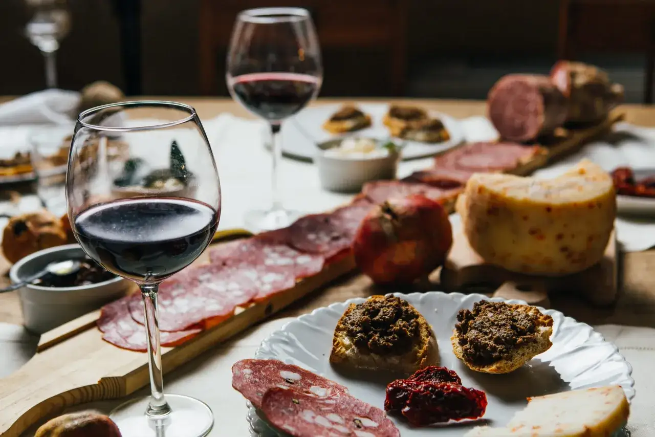 Un assaggio di cibi tipici toscani: salumi, formaggi, crostini con paté e vino rosso.