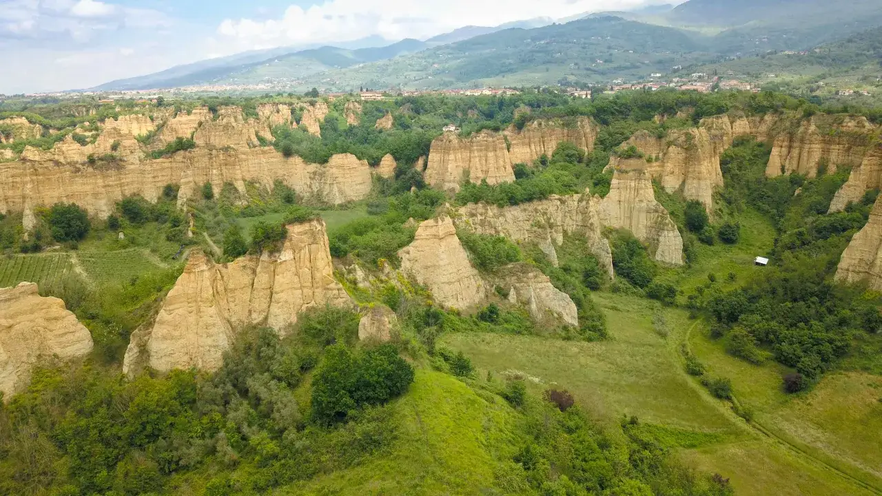 Paesaggio con calanchi e calanchi argillosi vicino a Castelfranco di Sopra, con un piccolo edificio bianco in lontananza.