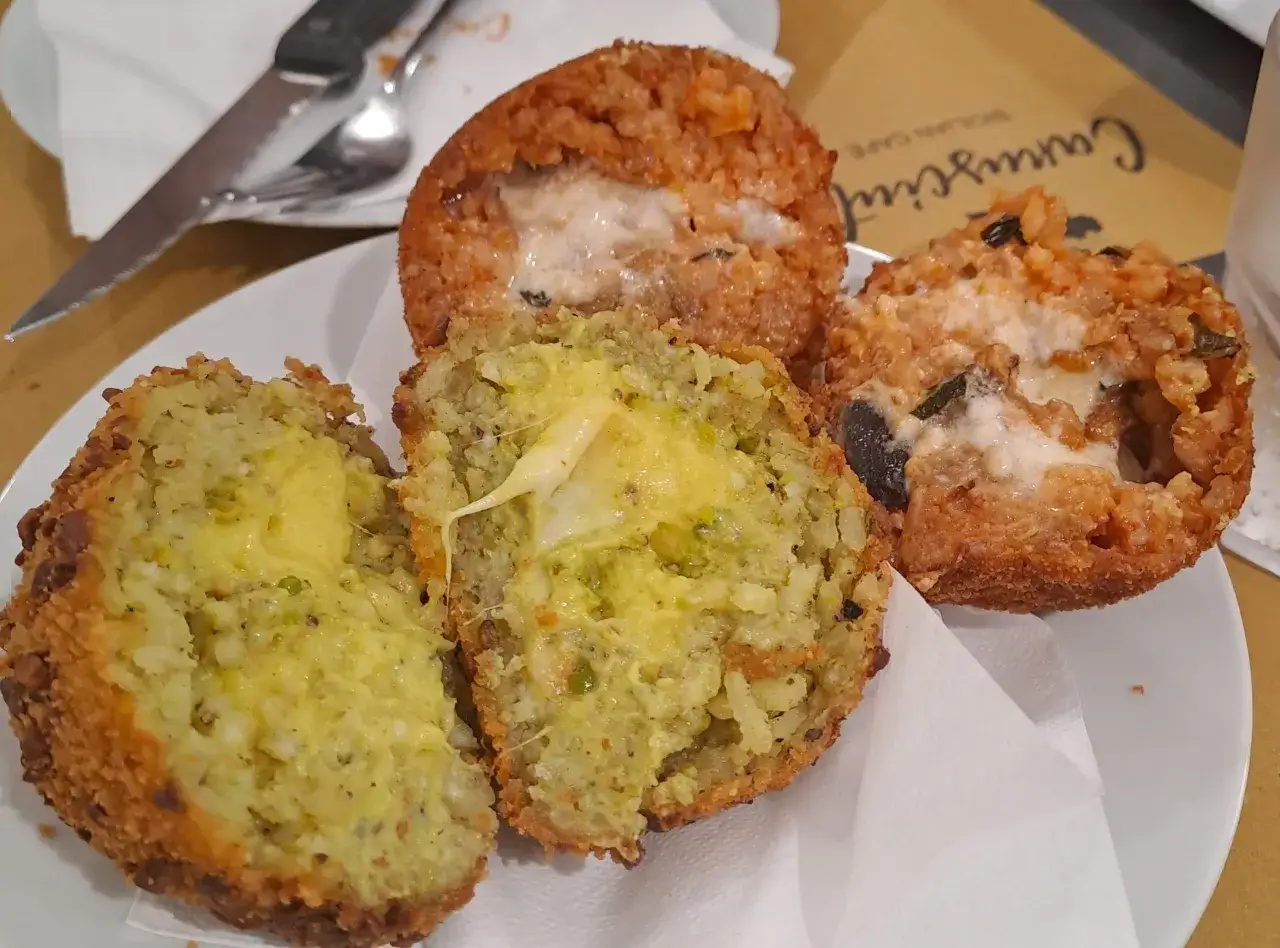 Arancini ripieni, un classico su cosa mangiare a Catania. Croccanti fuori, morbidi e filanti dentro, un'esplosione di sapori.