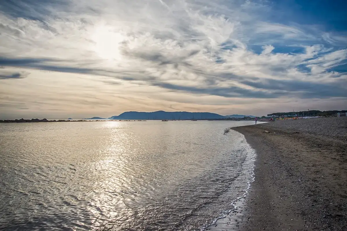 Spiaggia e mare calmo al tramonto, con montagne all'orizzonte. Un angolo di pace nella provincia di Massa e Carrara.