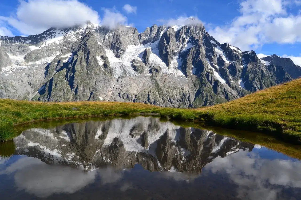 Riflesso di montagne innevate in un laghetto alpino, un'immagine mozzafiato di cosa vedere a Courmayeur.