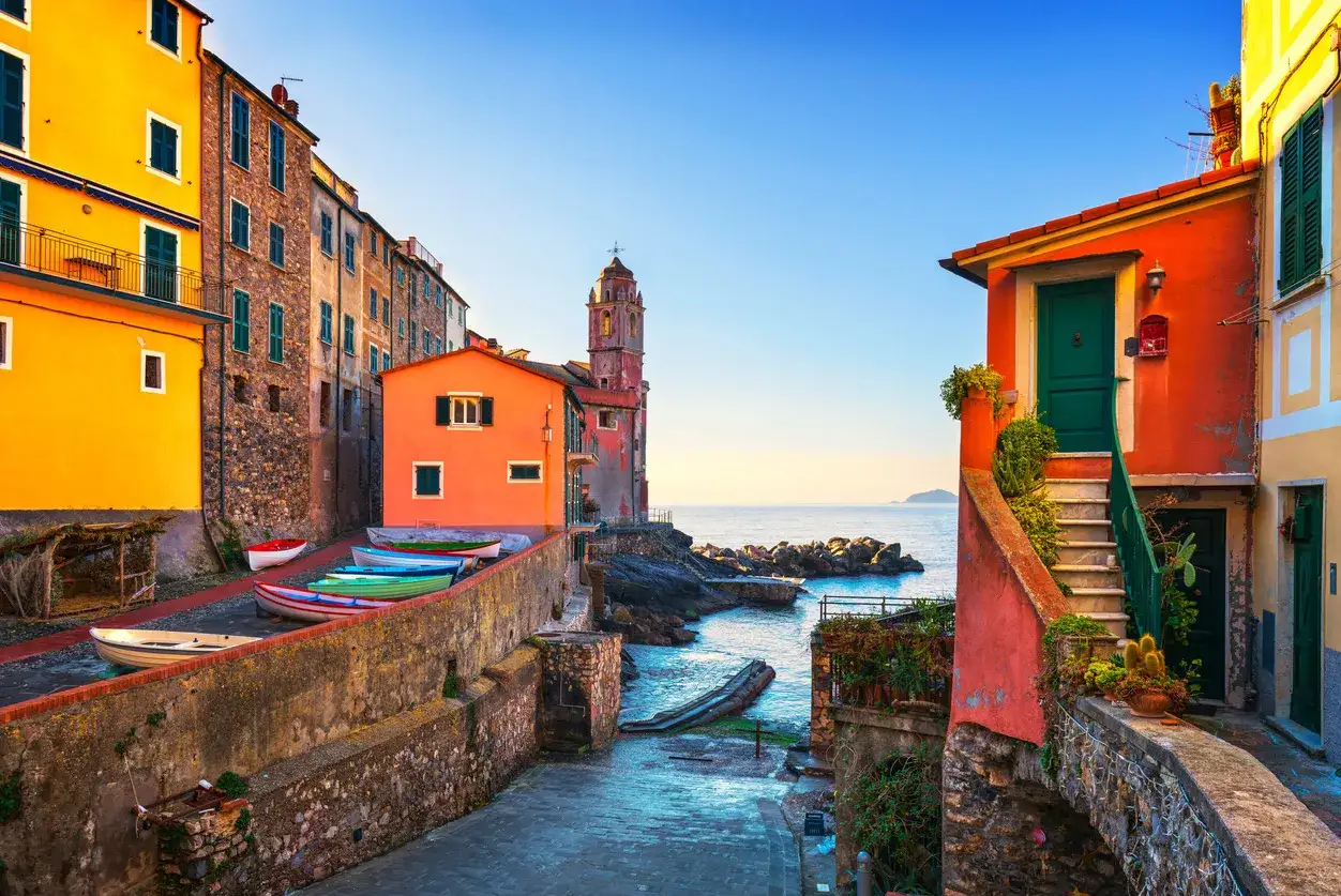 Colorate case a picco sul mare, barche a remi allineate e un campanile svettano nel paesaggio mozzafiato delle Cinque Terre.