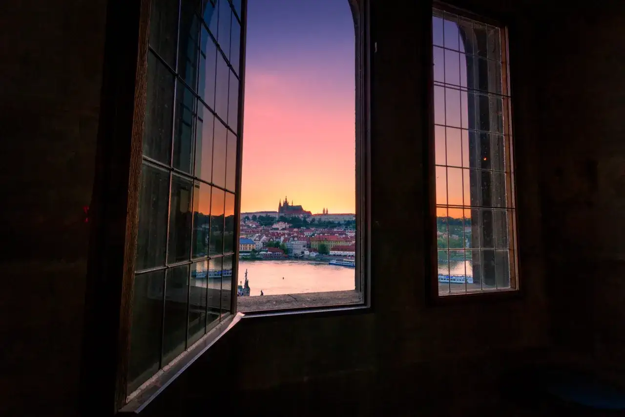 Tramonto su Praga visto da una finestra. Perfetto per un itinerario Praga 3 giorni, con il castello e il fiume Moldava.
