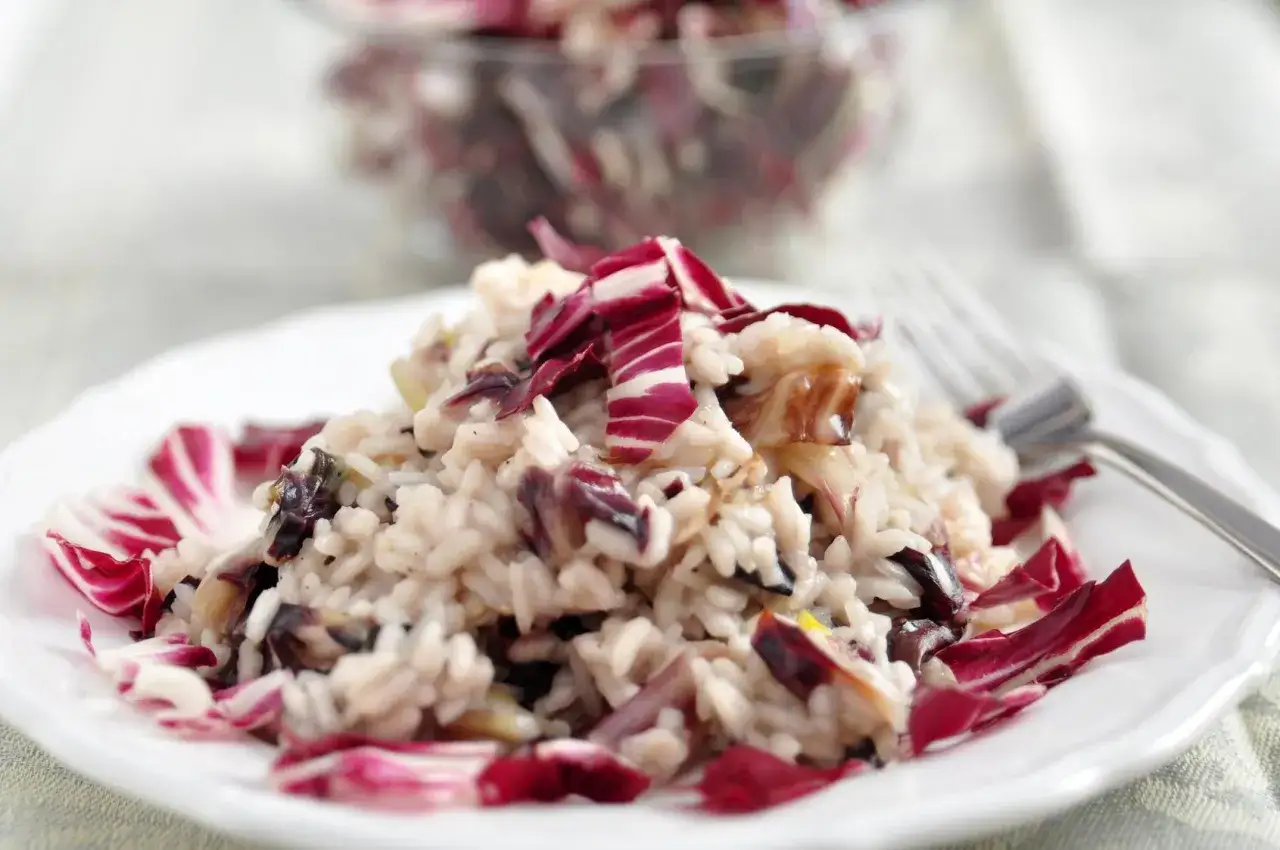 Risotto al radicchio, un classico da provare se ti chiedi cosa mangiare a Treviso. Cremoso e saporito, con le foglie rosse che danno un tocco di colore.