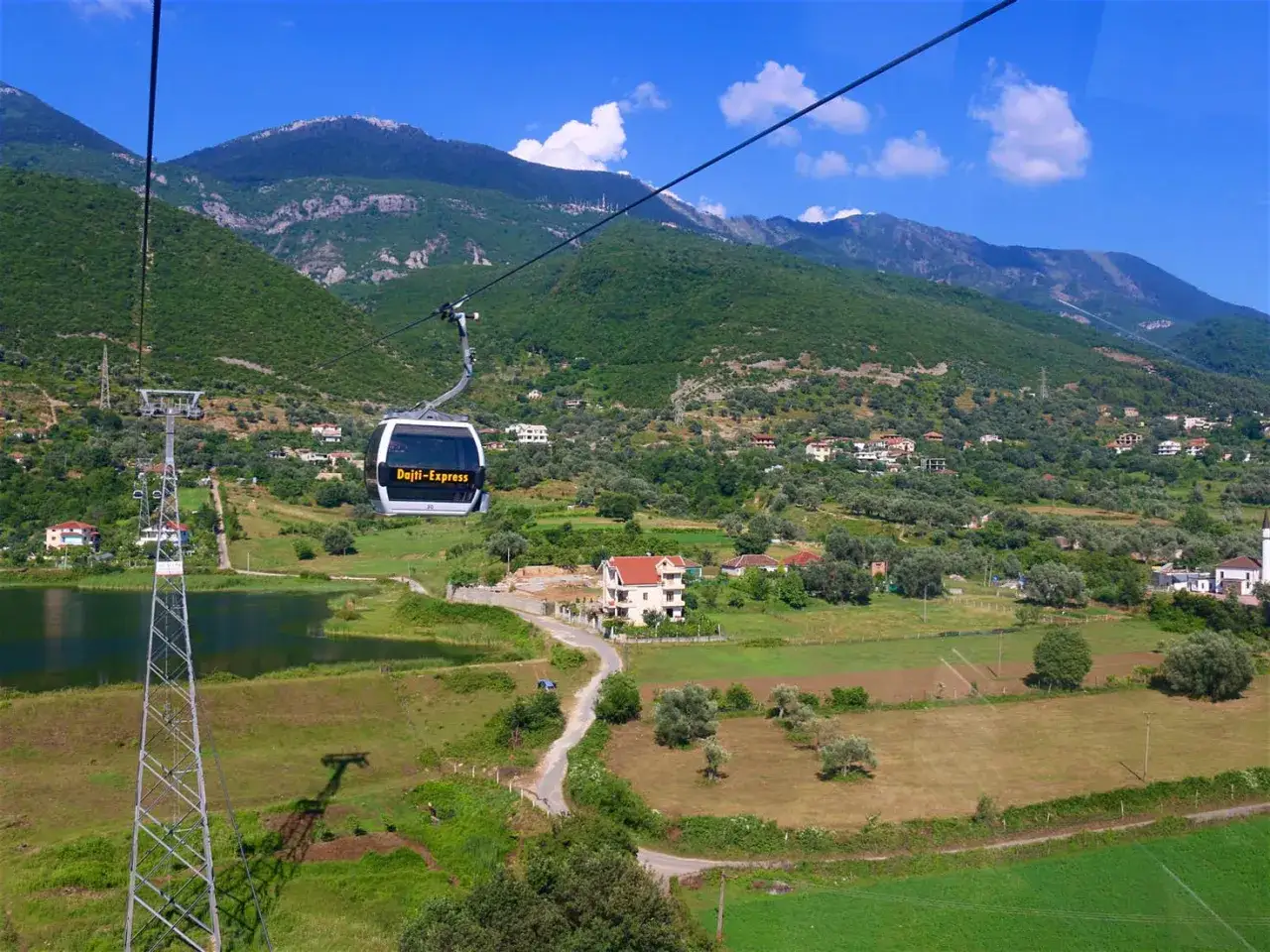 La funivia Dajti Express offre una vista panoramica su villaggi e uliveti, mostrando dove si trova Tirana, con montagne verdi sullo sfondo.