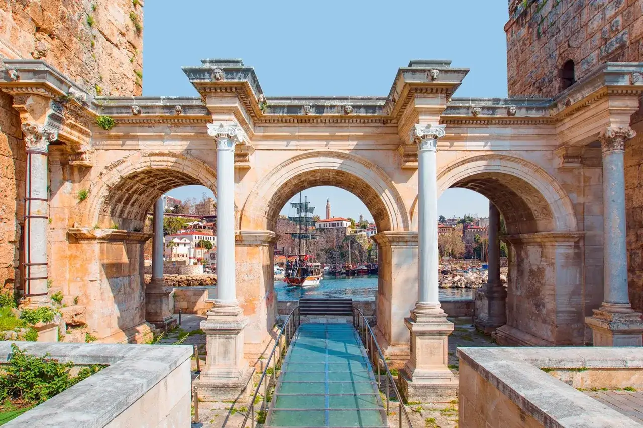 Arco di Adriano, Antalya: un portale storico con vista sul porto e su un veliero. Imperdibile tra le cose da vedere ad Antalya.