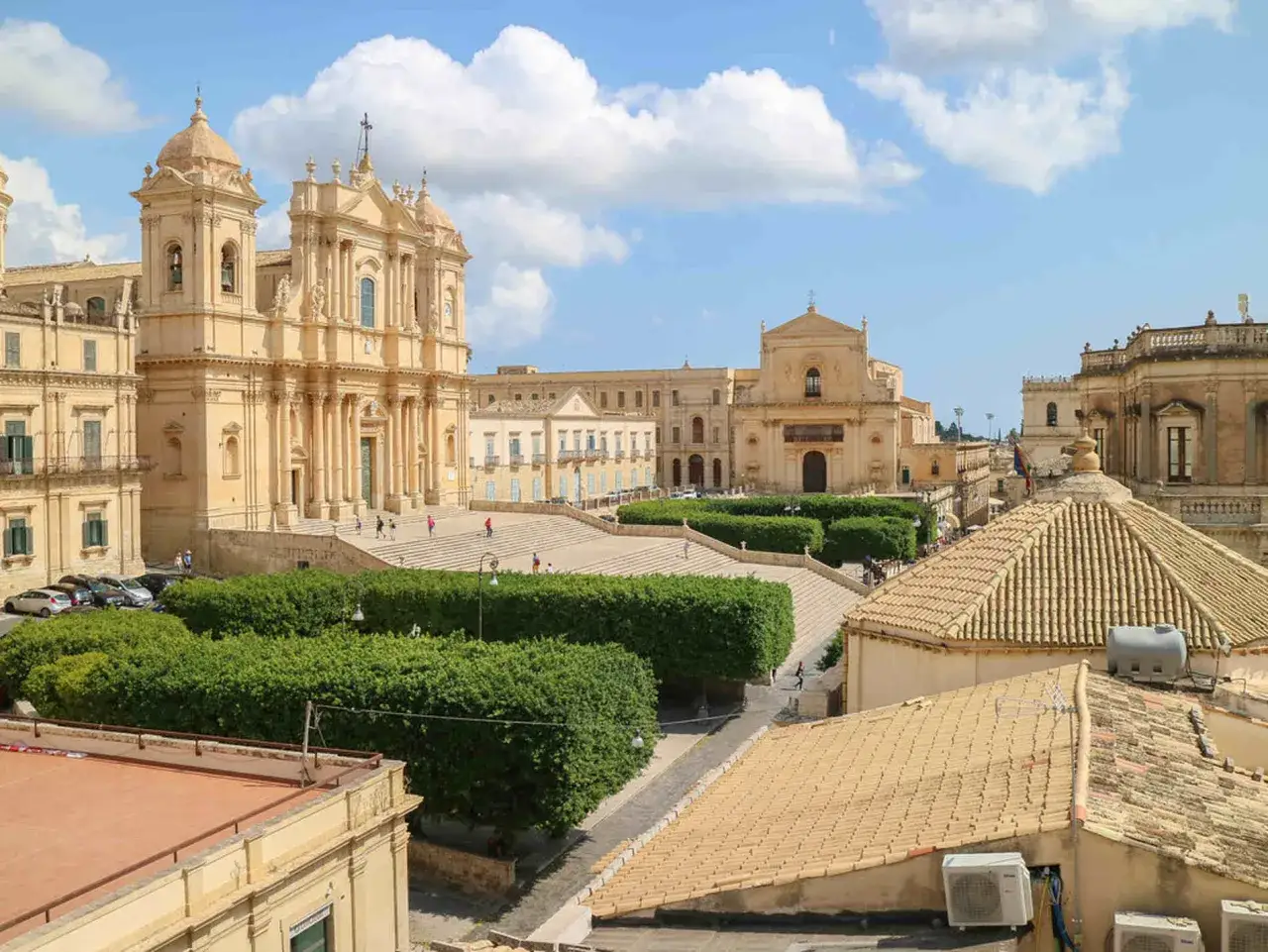 Piazza barocca con la cattedrale di Noto, una delle citta piu belle d'Italia, sotto un cielo azzurro con nuvole bianche.