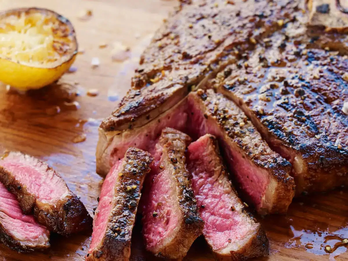Succulenta bistecca alla fiorentina affettata, cotta al punto giusto, con limone grigliato. Perfetta per scoprire dove mangiare la fiorentina a Firenze.