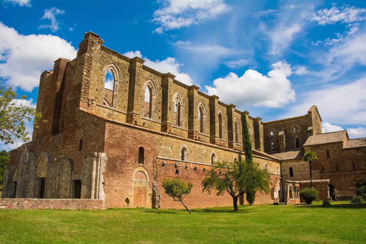 Imponente abbazia in rovina nel Val di Merse, con archi gotici e cielo azzurro.