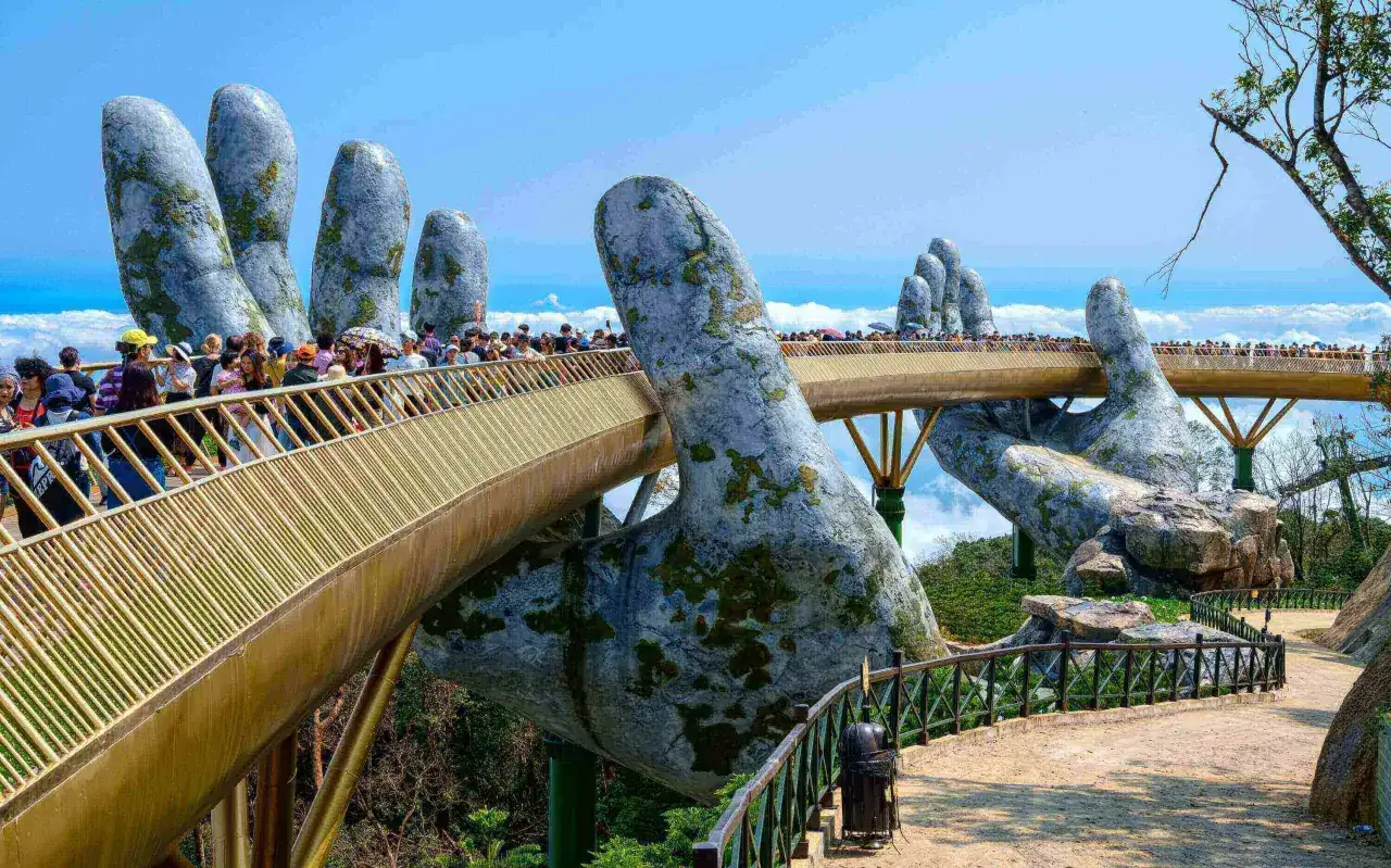 Ponte d'Oro in Vietnam, un'esperienza imperdibile tra le nuvole, con mani giganti che sorreggono un ponte dorato.