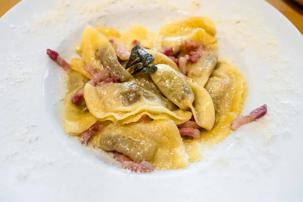 Ravioli ripieni, conditi con pancetta e salvia, un classico dei piatti tipici bergamaschi, spolverati di formaggio grattugiato.