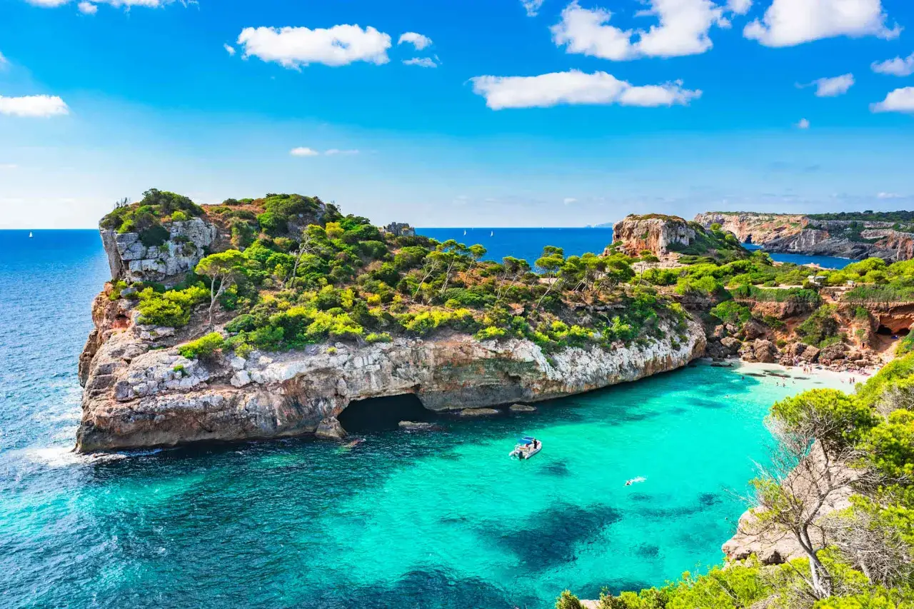 Baia con acque turchesi cristalline, scogliere verdi e una piccola spiaggia, tra le palma di maiorca spiagge più belle.