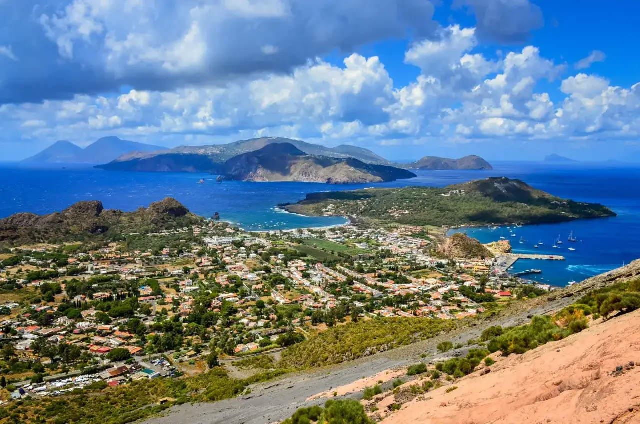 Panoramica mozzafiato delle isole siciliane più belle, con case bianche, mare blu intenso e montagne verdi.