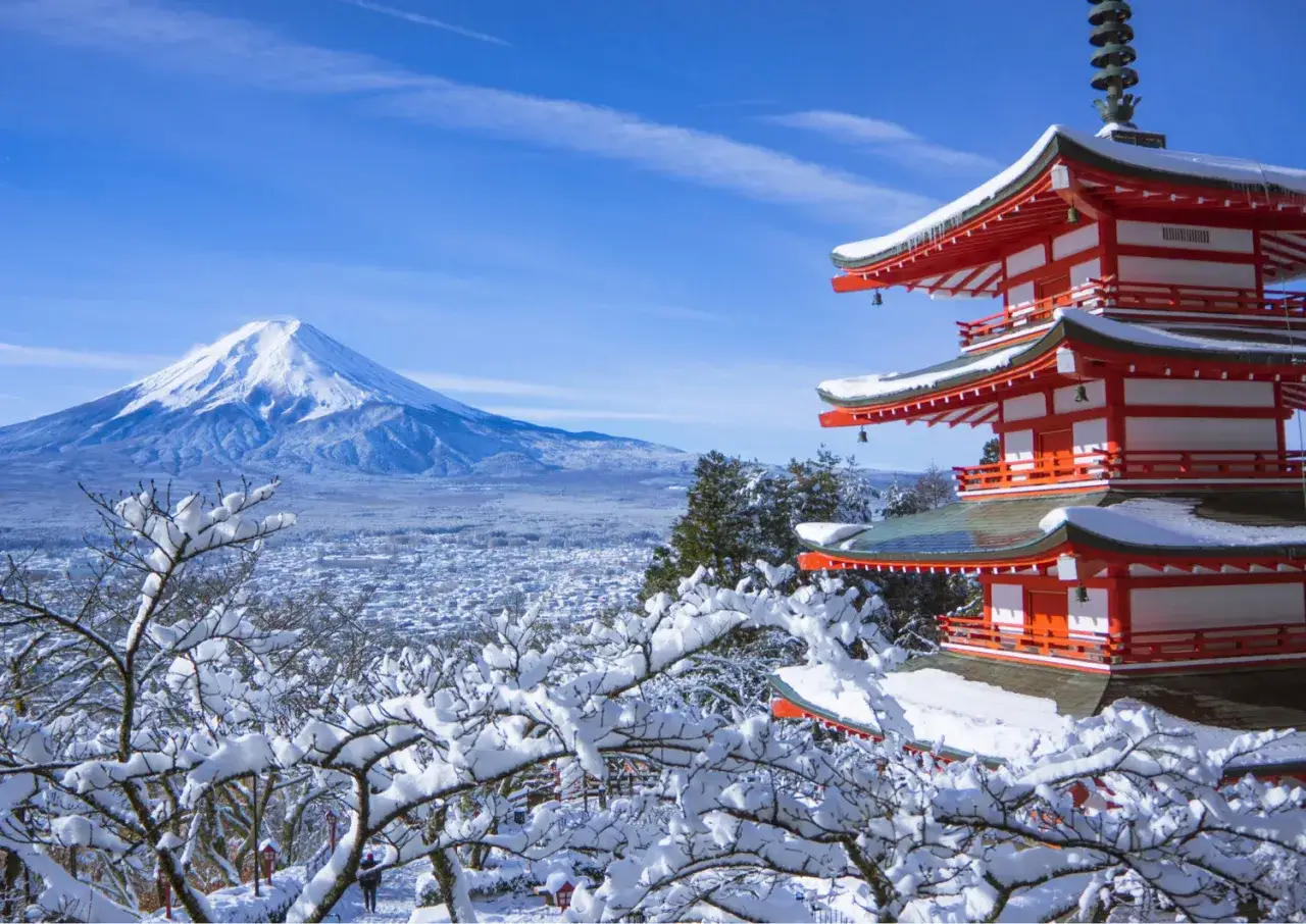 Pagoda rossa innevata con il Monte Fuji sullo sfondo, un'immagine iconica di cosa vedere in Giappone in inverno.