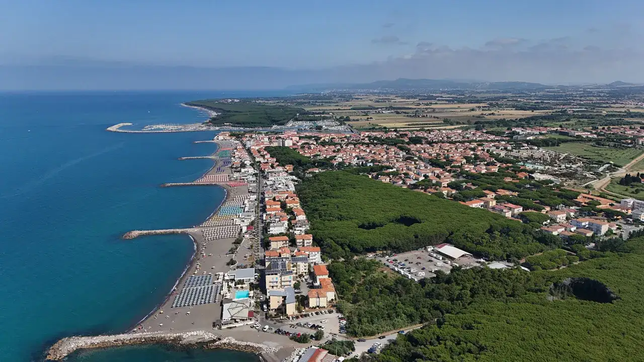 Vista aerea della marina di Cecina lungomare con spiagge attrezzate, mare azzurro, pineta e case.
