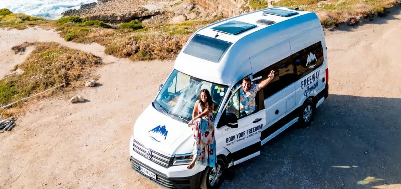 Coppia felice in vacanza in Sardegna in camper, godendosi la costa selvaggia.