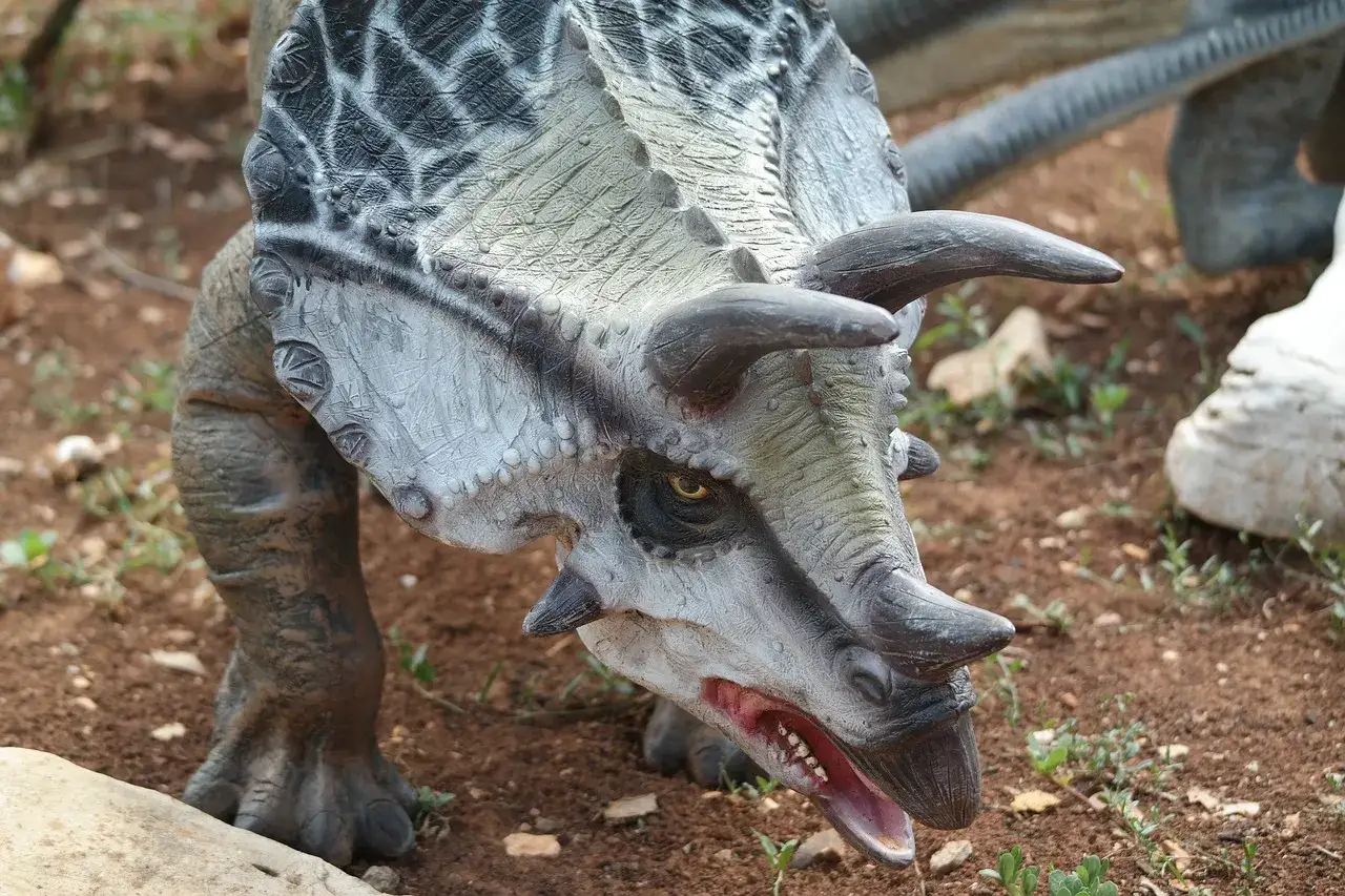 Dettaglio di un dinosauro con corna e bocca aperta, un'attrazione del zoo più grande d'Italia.