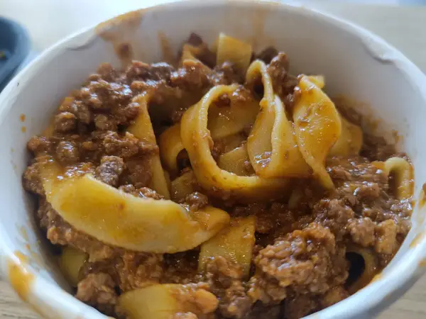 Tagliatelle al ragù, un classico su cosa mangiare a Bologna. Pasta fresca con sugo di carne saporito in una ciotola.