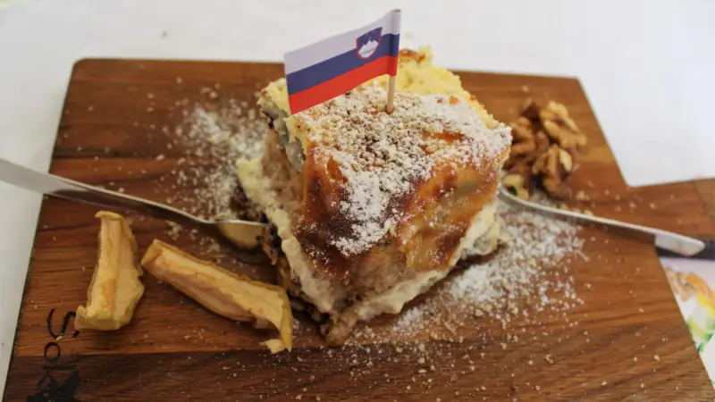 Fetta di torta con bandiera slovena, noci e mele essiccate, un assaggio dei piatti tipici sloveni.